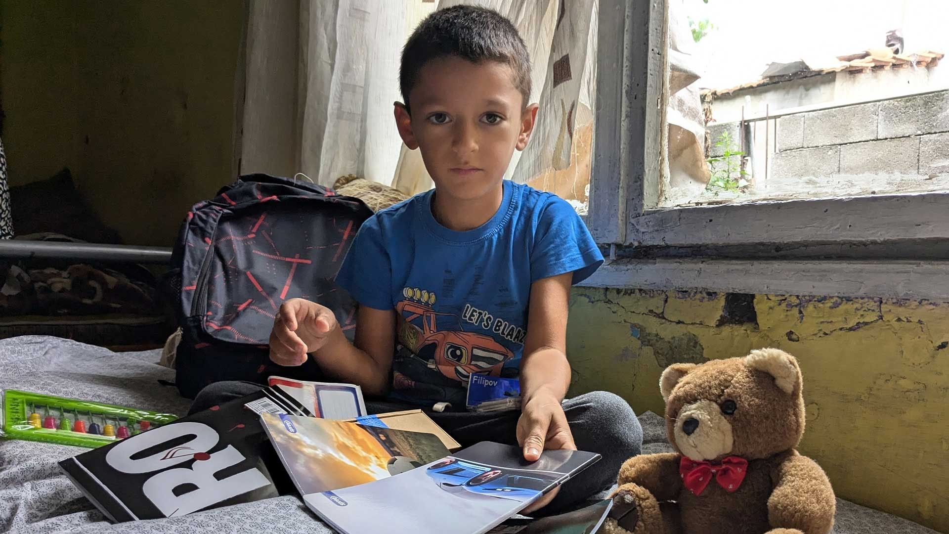 A boy sits in his room.
