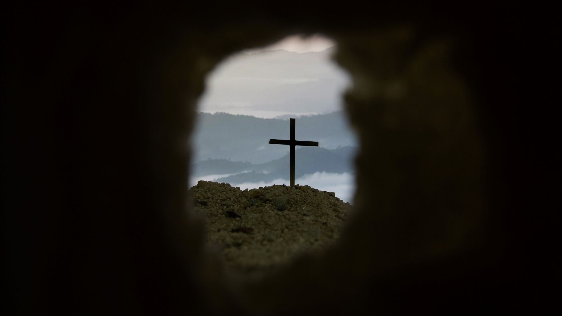 View of a cross outside, seen from inside an empty tomb.