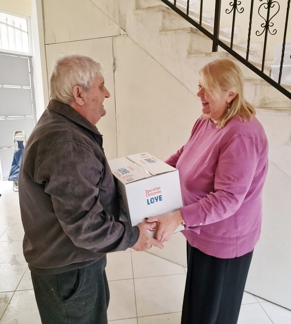 Monica delivering an Operation Christmas Love parcel to an elderly gentleman