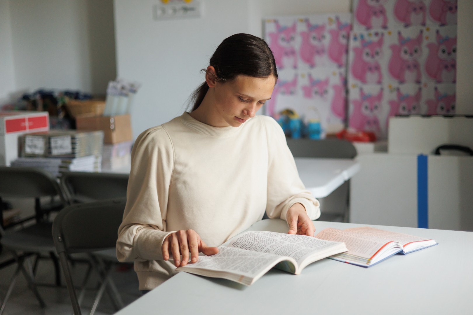 A girl sitting with open books at a table.