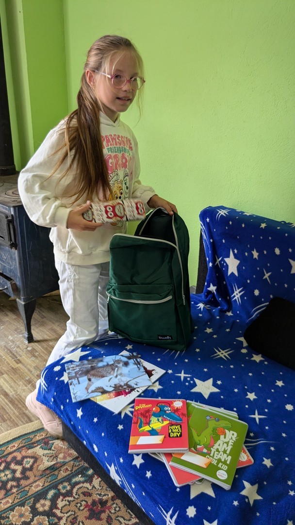 A girl organizing her new backpack received from Mission Without Borders