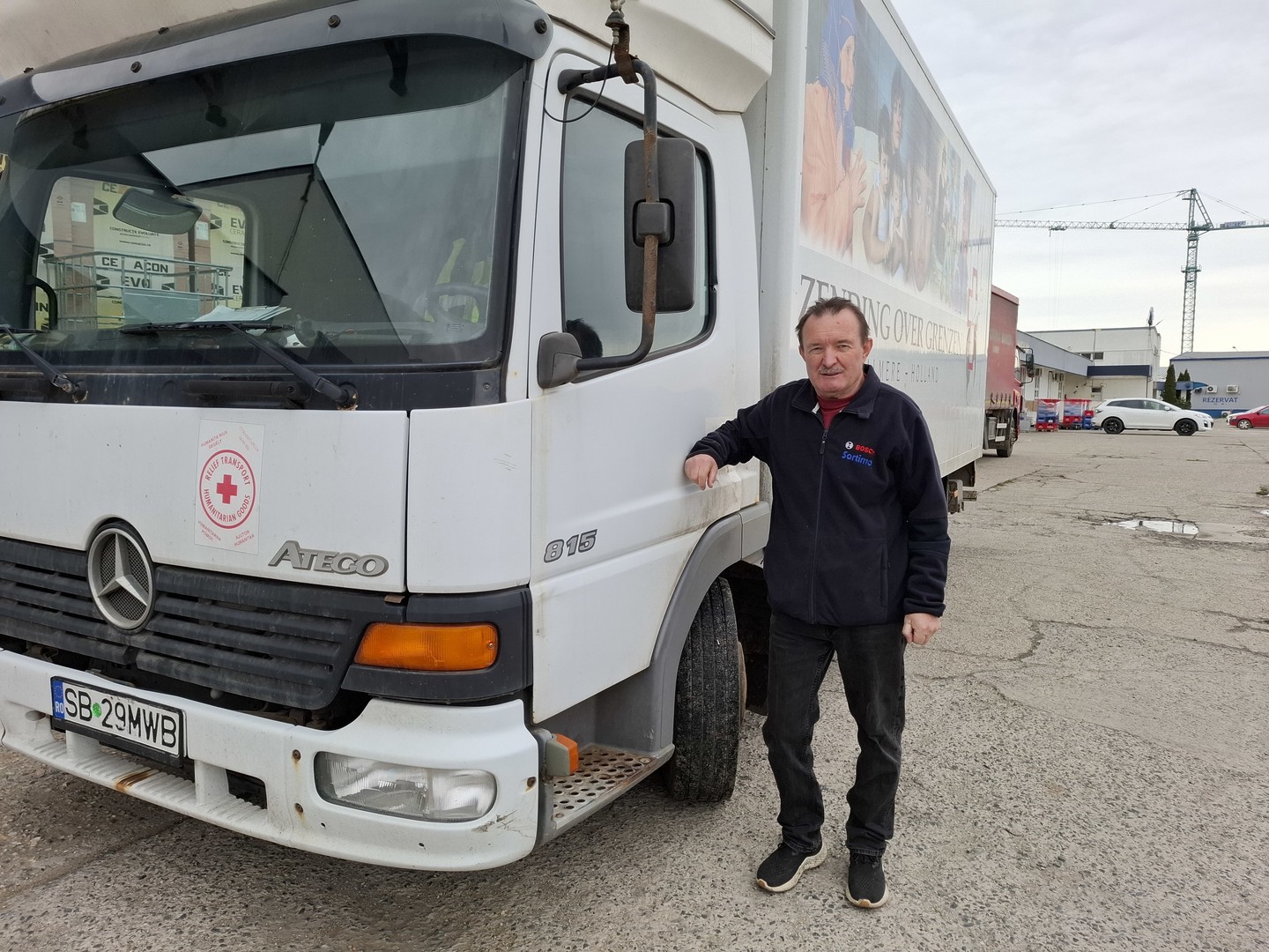 A man leaning on the driver's door of his delivery truck