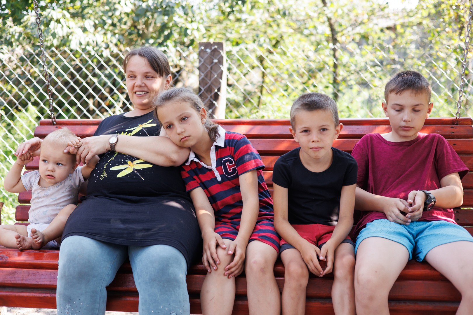 A mother sitting on a bench with four children